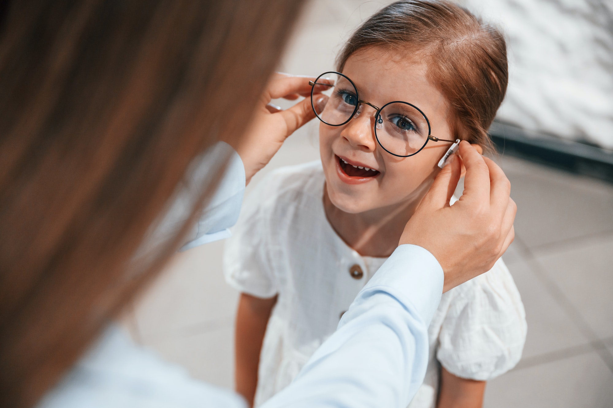 Wearing new eyewear. Woman and girl is in the glasses store